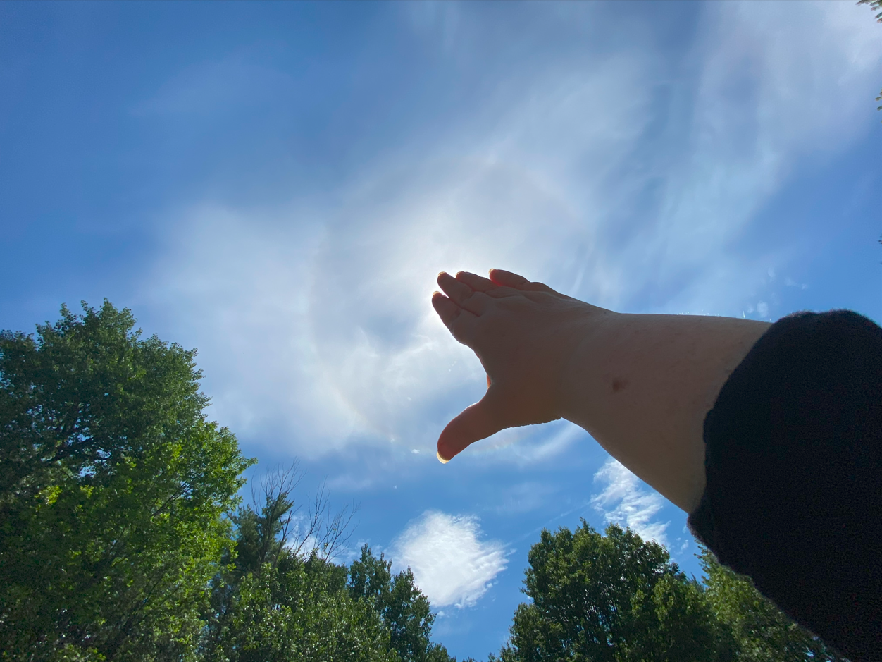 The 22° halo is relatively common and easy to identify. With your arm fully extended and using your hand to block the sun (which you should not look at directly), it is also easy to verify. The distance between the tip of your thumb and the tip of your pinkie finger with your hand fully extended is roughly 22° when your arm is also fully extended between your eyes and the sun. Another way to confirm a 22° distance can be done by, also with your arm extended, separating the thumb as much as possible from the rest of the fingers, putting the tip of your middle finger right at the position of the sun and the thumb will be roughly pointing somewhere along the circular halo (the method shown in this picture)