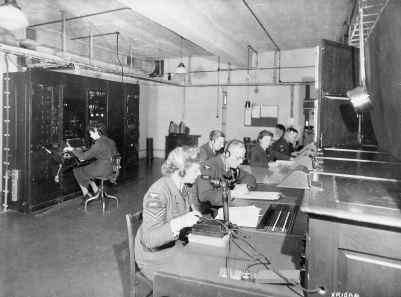 Black and white picture of white women and men sitting at a large desk